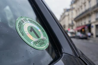 Vignette Crit'Air verte collée sur un pare-brise de voiture en centre-ville